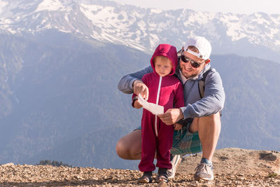 Happy father and son on the top of a mountain in rosa khutor are looking at a map of the area. 