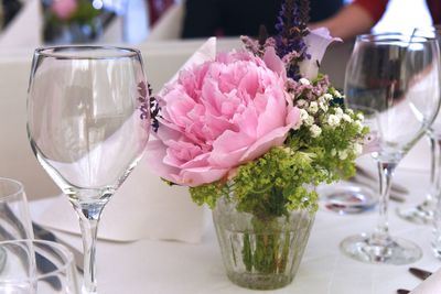 Close-up of flowers vase by wineglass on table