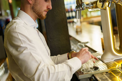 Midsection of bartender preparing drink at bar