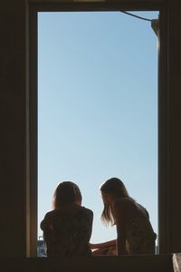 Rear view of women standing against sky