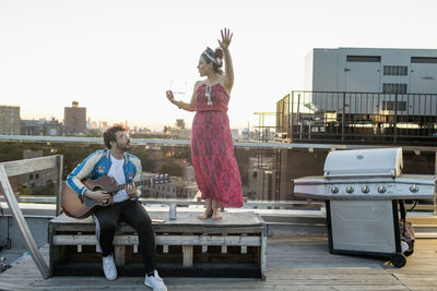 Young man playing guitar for his dancing friend