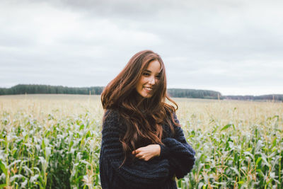 Smiling woman standing on field against sky