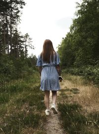 Rear view of woman standing on field against sky