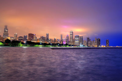 Illuminated buildings in city against sky