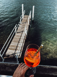High angle view of hand holding drink by lake