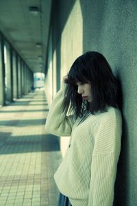 Sad young woman standing in corridor of building