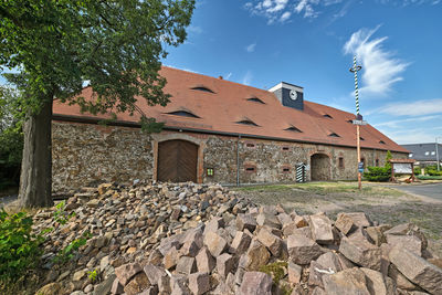 Stone wall of building and trees against sky