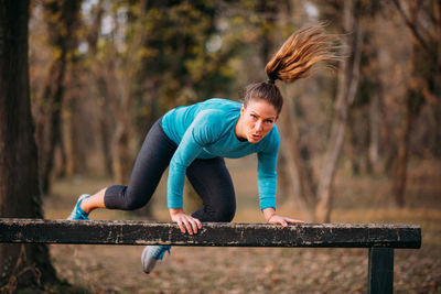 Portrait of woman exercising on bench in forest