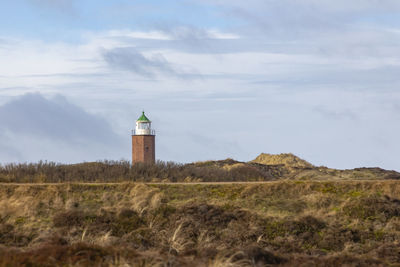 Lighthouse on field against sky