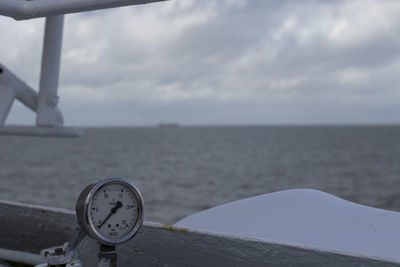 Close-up of clock on beach against sky