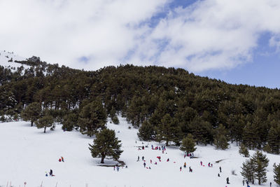 Group of people on snow covered land against sky