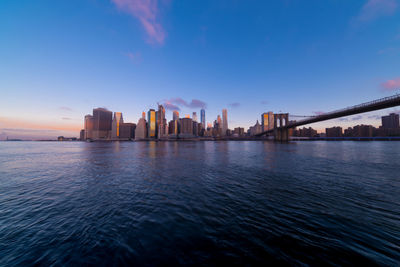 Scenic view of river by buildings against sky during sunset