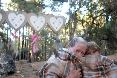 Portrait of couple covered under blanket in forest