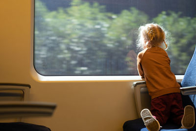 Little girl watching window while travelling by train. public transportation