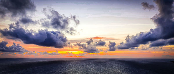 Panoramic view of sea against dramatic sky during sunset