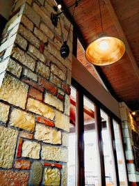 Low angle view of illuminated light bulb hanging from ceiling