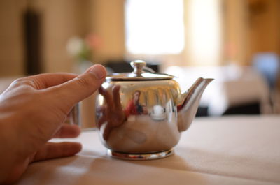 Close-up of hand holding tea cup on table