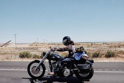 Rear view of people riding motorcycle on road