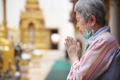 Woman with hands joined at temple