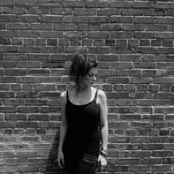Mid adult woman standing against brick wall
