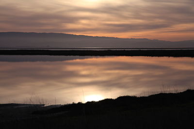 Scenic view of calm lake against cloudy sky