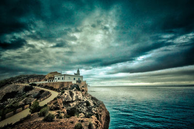 Lighthouse amidst sea and buildings against sky