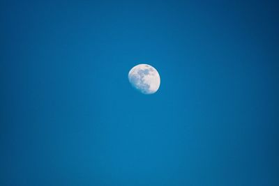 Low angle view of moon against blue sky