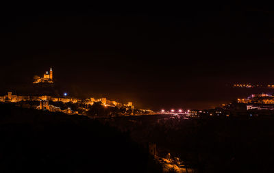 Illuminated cityscape against sky at night