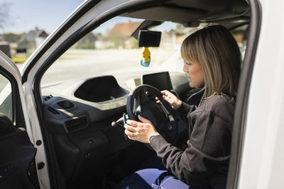 Female electrician sitting on driver's seat in van