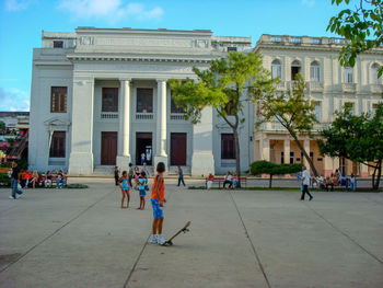 People standing by building in city against sky