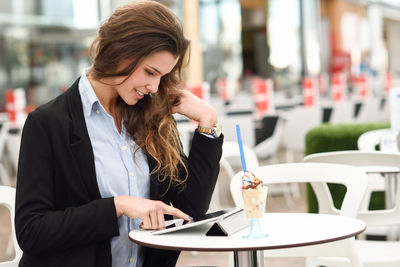 Businesswoman using digital tablet while having ice cream at outdoor cafe