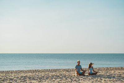 Young couple doing yoga at beach