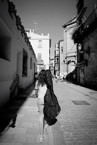 Rear view of people walking on street in city