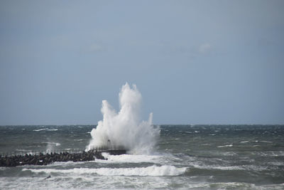 Waves splashing on shore against clear sky