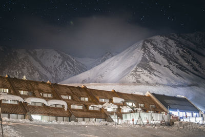 Houses and snowcapped mountain against sky at night