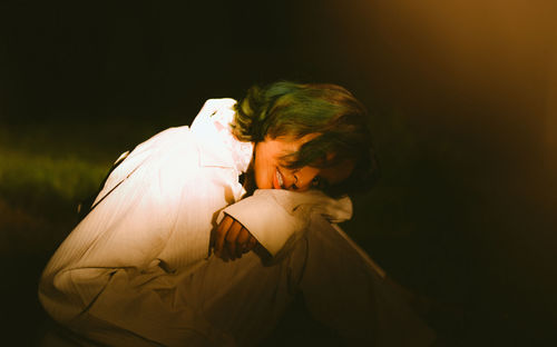 Side view of woman looking at camera at night