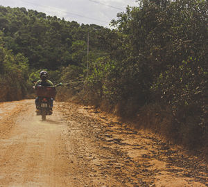 Rear view of man riding motorcycle on road