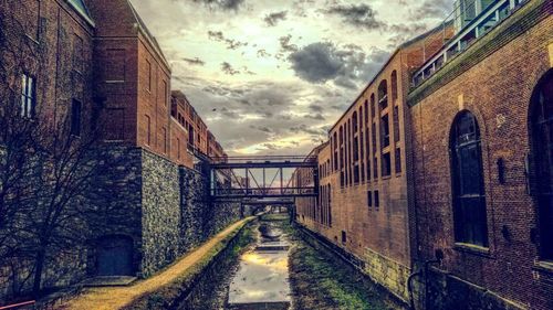 Empty road amidst buildings against sky