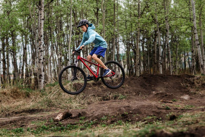 Teen boy on mountain bike at dirt park doing jumps