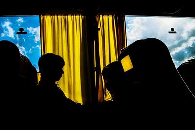 Silhouette people sitting in glass window