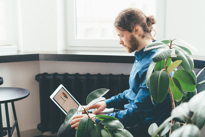 Young man looking away while sitting at home