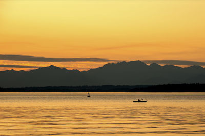 Kayaker paddling by the olympic mountains during golden hour.