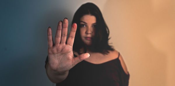 Portrait of young woman standing against wall