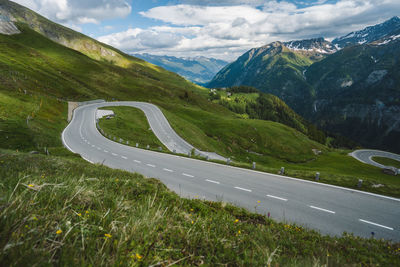 Scenic view of road by mountains against sky