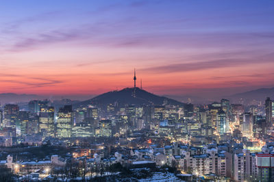 Illuminated cityscape against sky at sunset