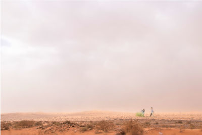 Man standing on desert land against sky