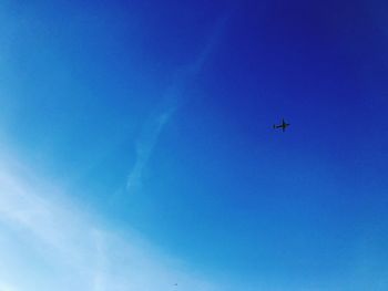 Low angle view of airplane flying against clear blue sky