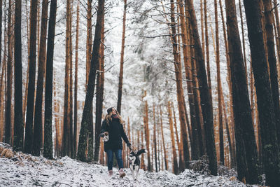 Man standing amidst trees in forest during winter