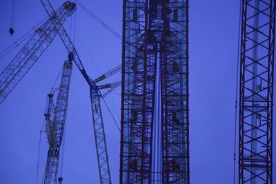 Cranes at construction site against blue sky