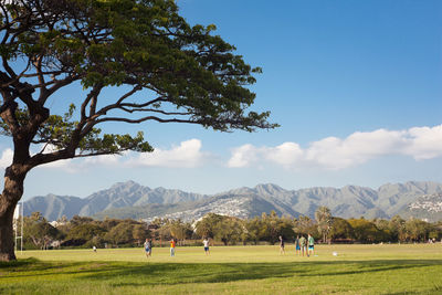 People on field by mountains against sky